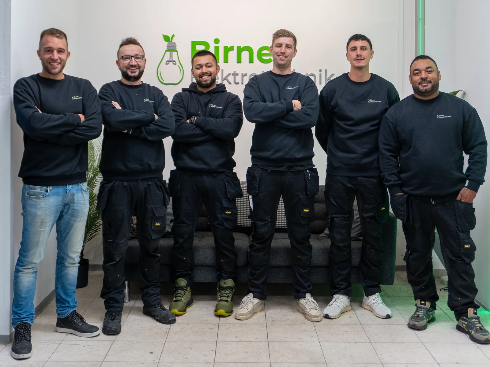 Das Team von Birner Elektrotechnik, sechs Kollegen in Arbeitskleidung vor dem Firmenlogo